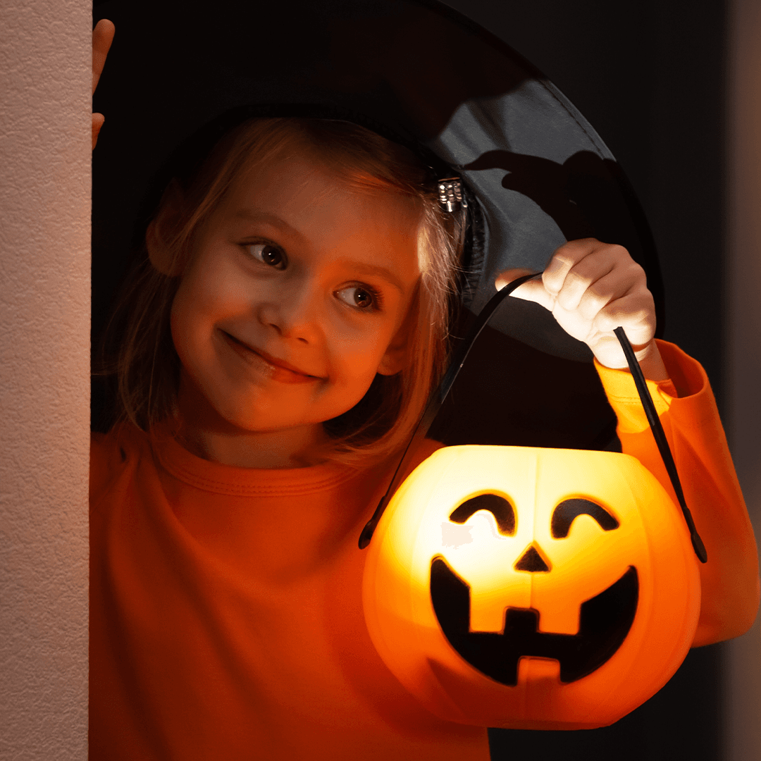Tyttö pitelee kurpitsalyhtyä halloween-juhlassa
